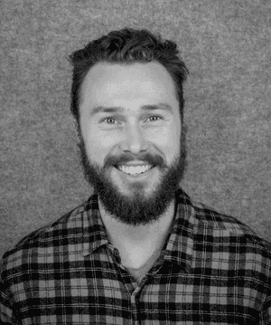 A black & white portrait of Stile team member Matthew Needham smiling at the camera