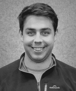 A black & white portrait of Stile team member Nick Spain smiling at the camera